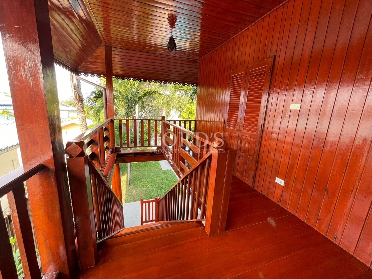 Wooden villa staircase and upper-level hallway with polished hardwood floors, railing, and garden view.