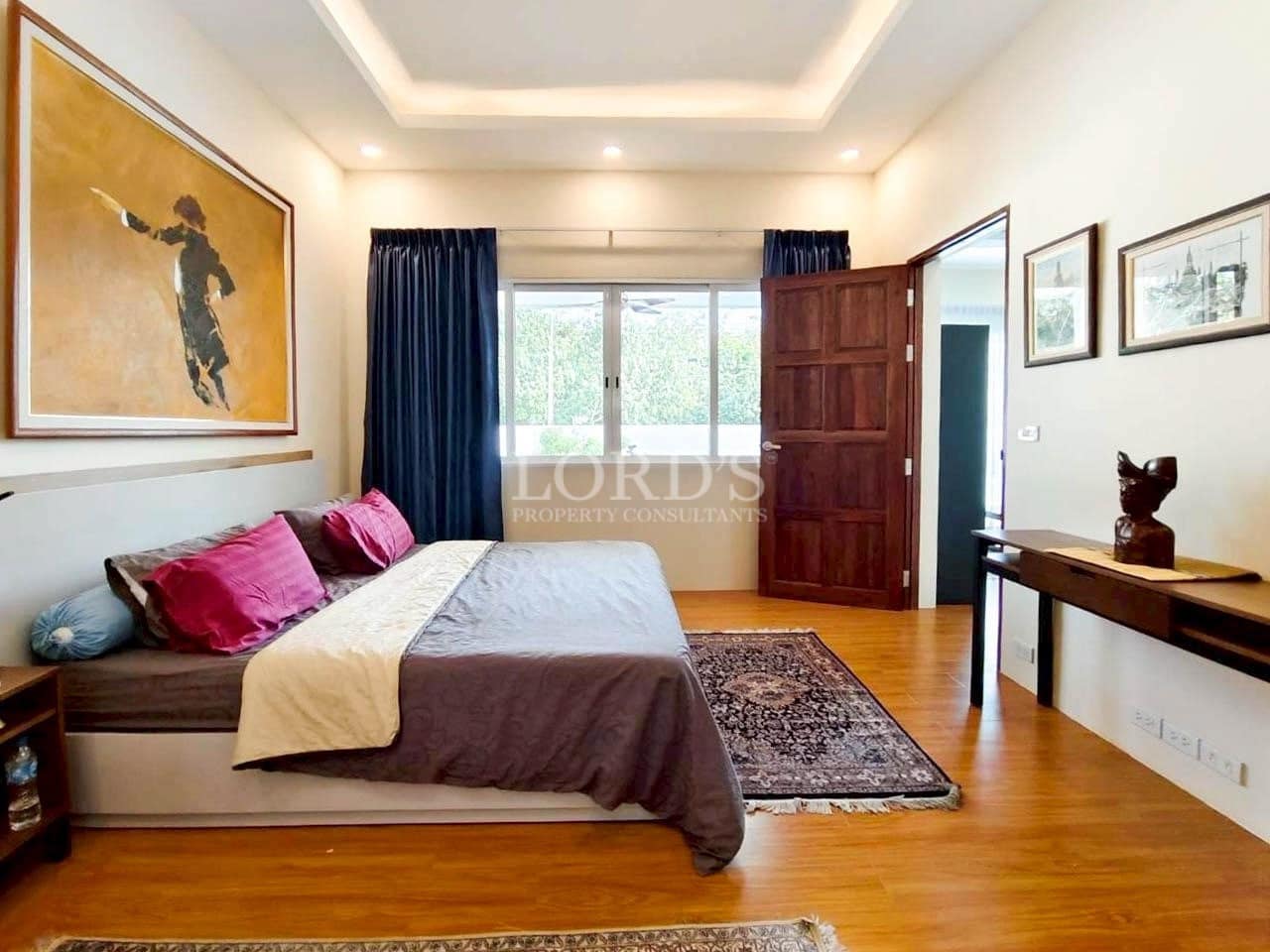 Modern bedroom with wooden flooring, minimalist furniture, and large window with curtains.