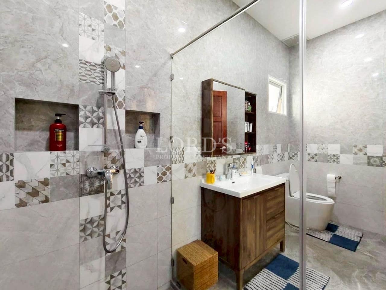 Contemporary bathroom with patterned tiles, glass shower enclosure, and wooden vanity.