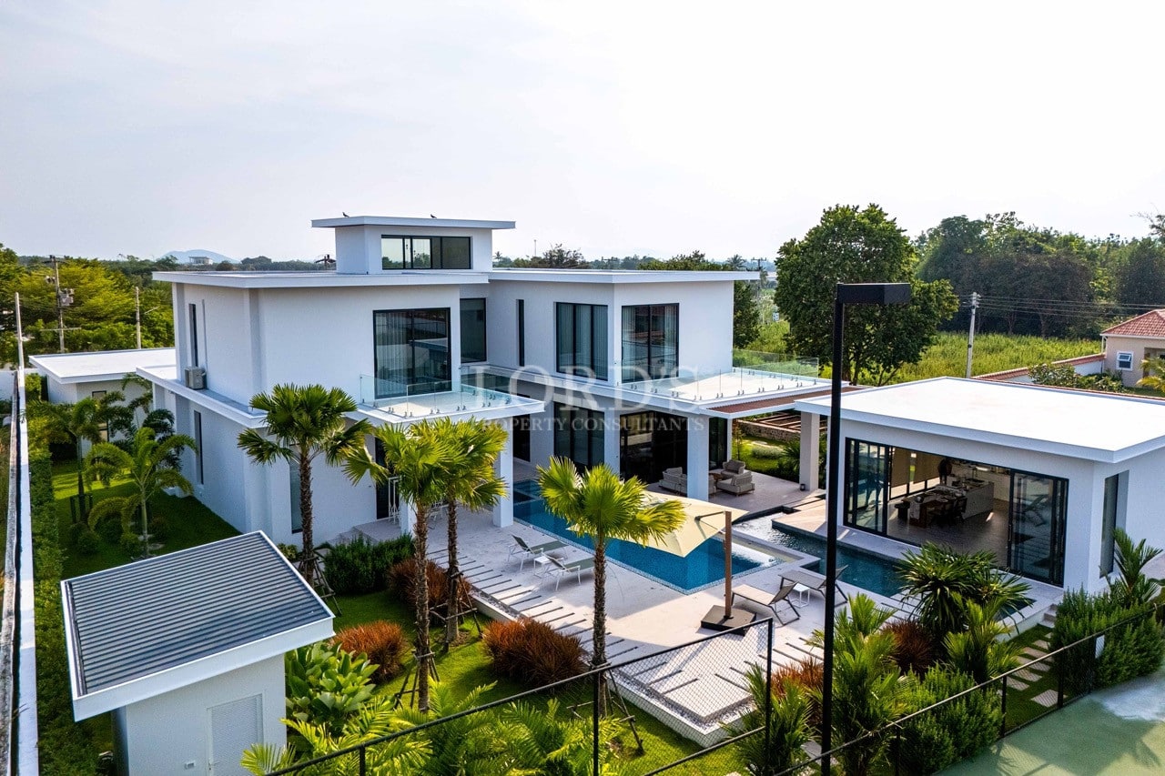 Aerial view of a modern luxury villa with private swimming pool, glass balconies, and landscaped tropical garden.