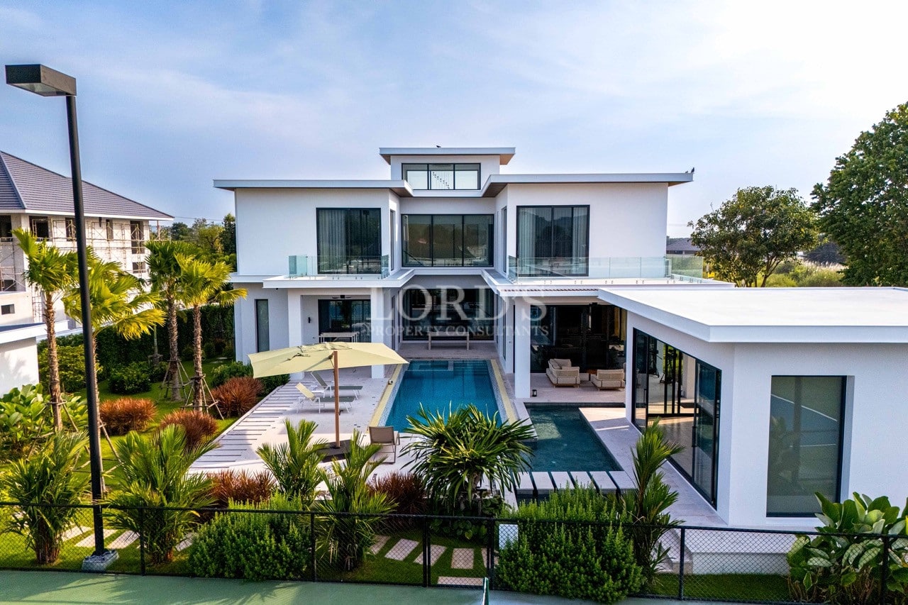 Front view of a modern luxury villa with private swimming pool, glass balconies, and landscaped garden.