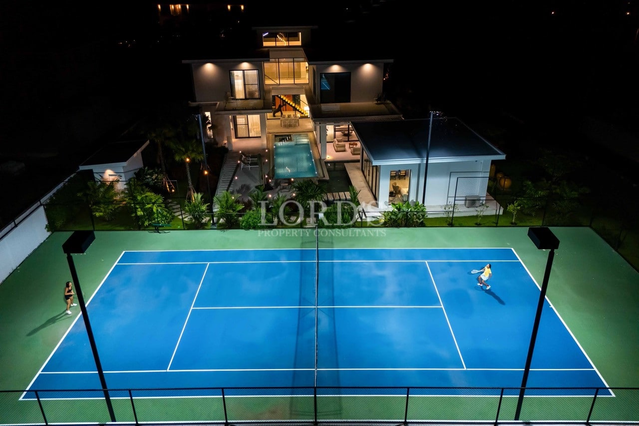 Luxury villa at night with private tennis court, swimming pool, and modern architectural lighting.