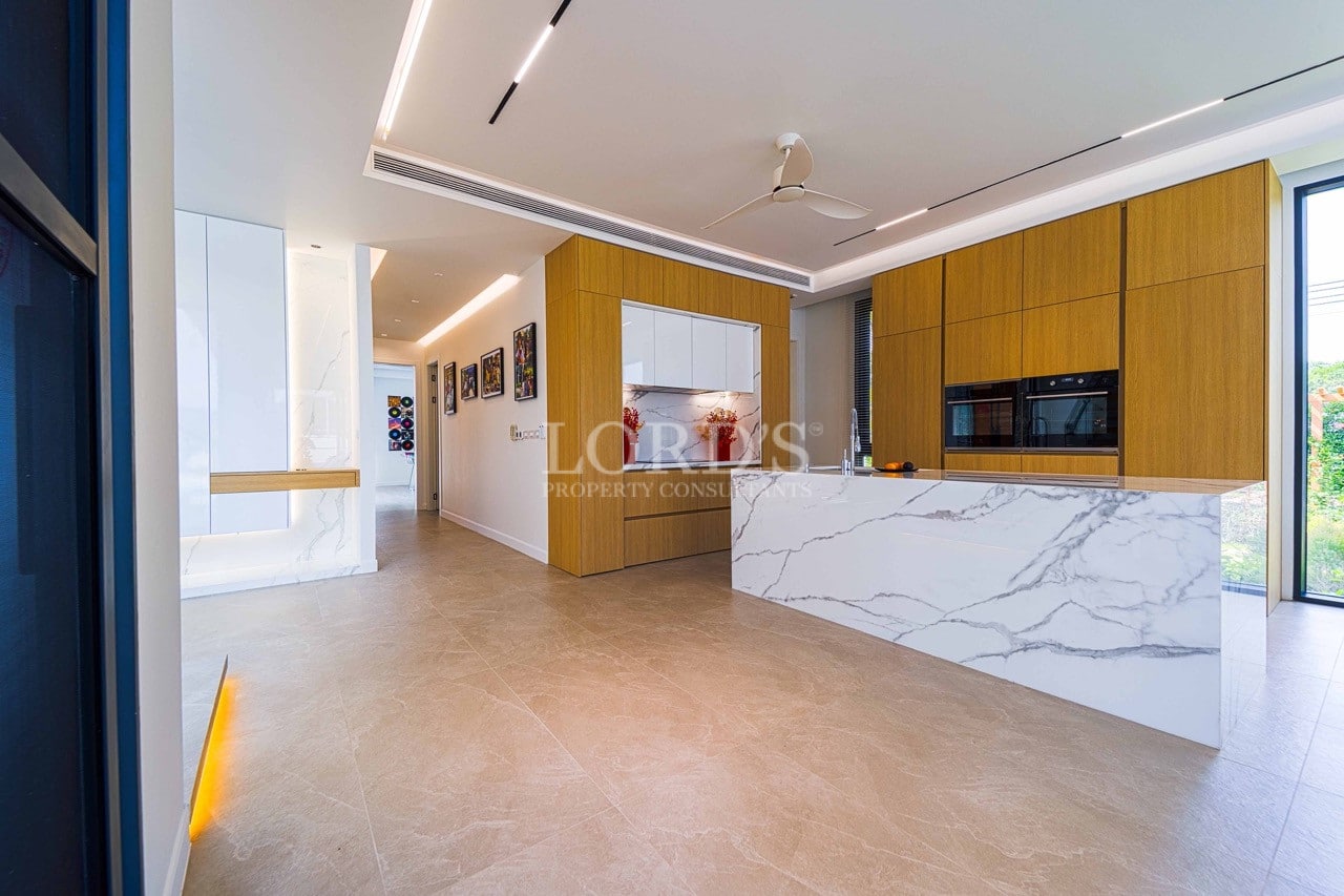 Modern open-plan kitchen with marble island, wood cabinetry, built-in appliances, and recessed ceiling lighting.