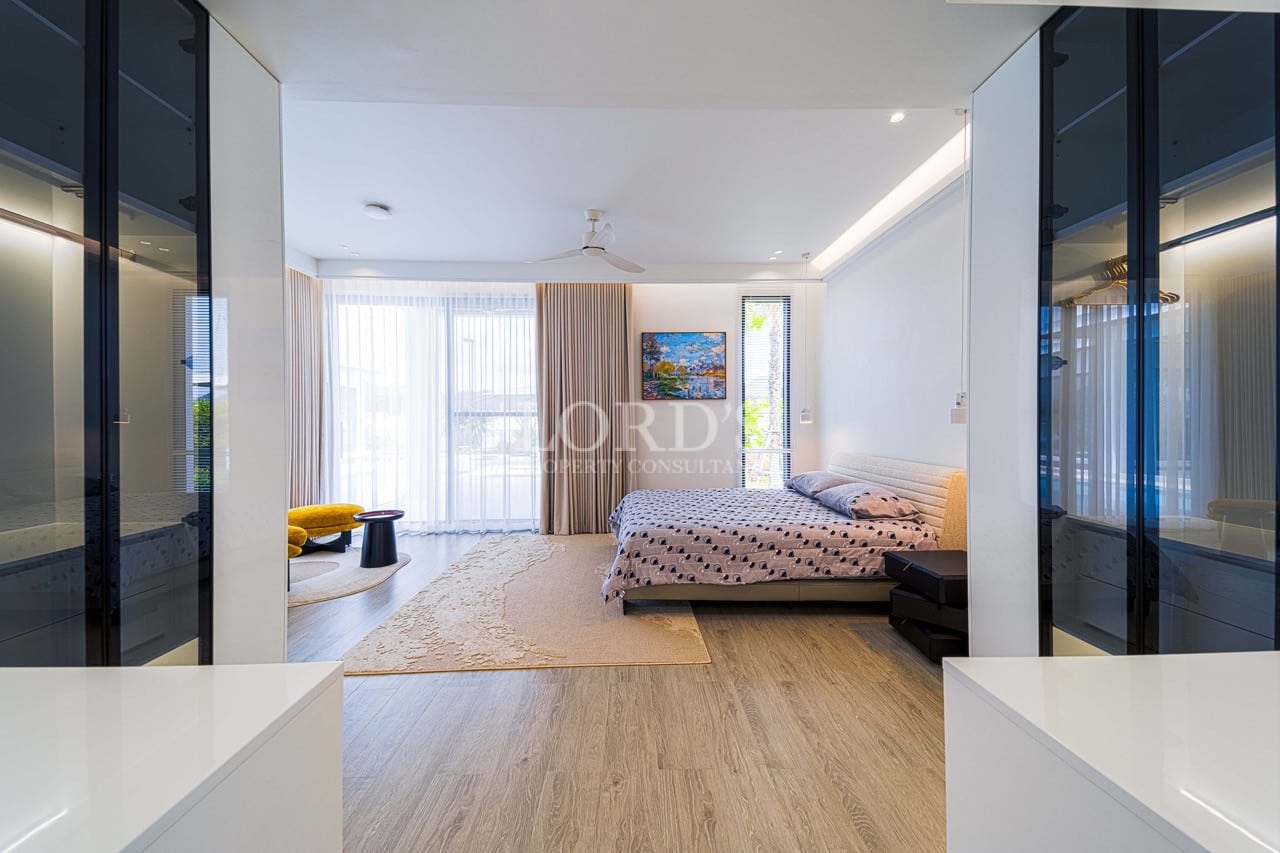 Modern luxury bedroom with walk-in wardrobe, soft natural lighting, wooden flooring, and minimalist interior design.