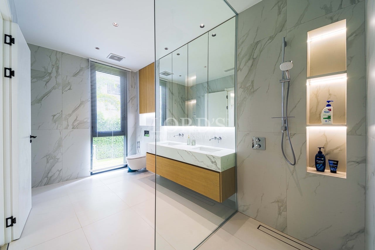 Modern luxury bathroom with marble walls, glass shower enclosure, floating vanity, and recessed illuminated shelves.