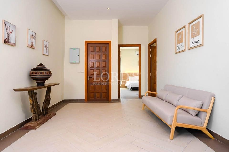 Minimalist villa hallway with wooden doors, modern sofa, and neutral interior design.