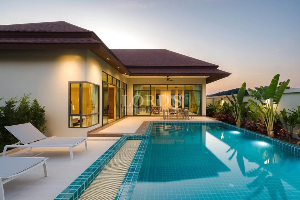 Luxury modern villa with private swimming pool and outdoor seating at sunset.