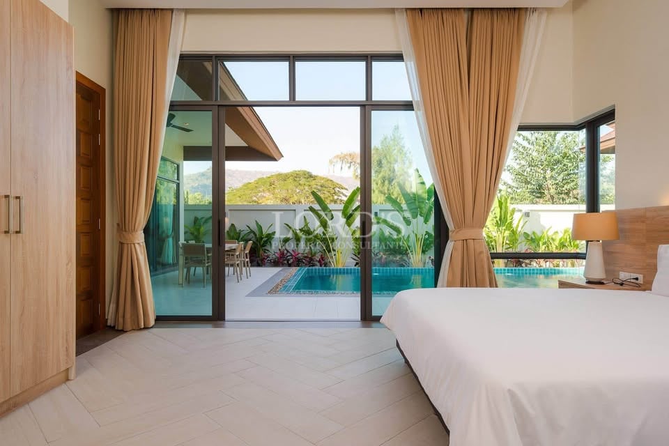 Modern bedroom with floor-to-ceiling glass doors opening to private pool and garden view.
