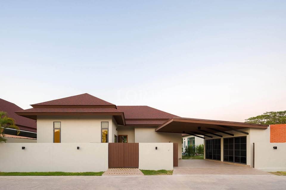 Modern villa exterior with covered carport, boundary wall, and gated entrance.