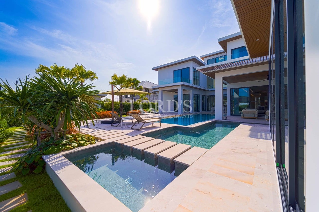 Modern luxury villa with private swimming pool, sun loungers, tropical landscaping, and seamless indoor–outdoor design.