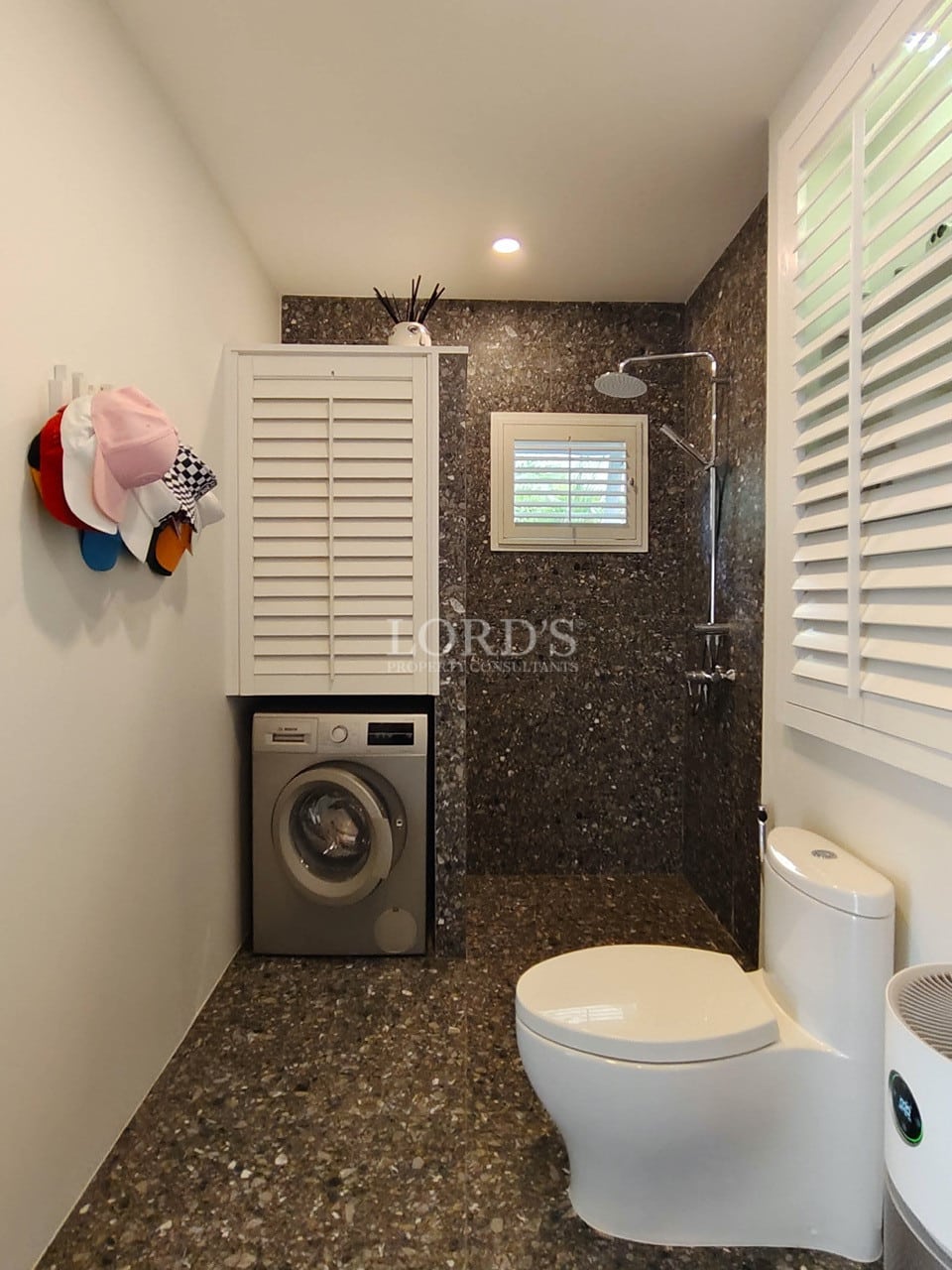 Modern bathroom with walk-in shower, washing machine, stone finishes, and compact design.