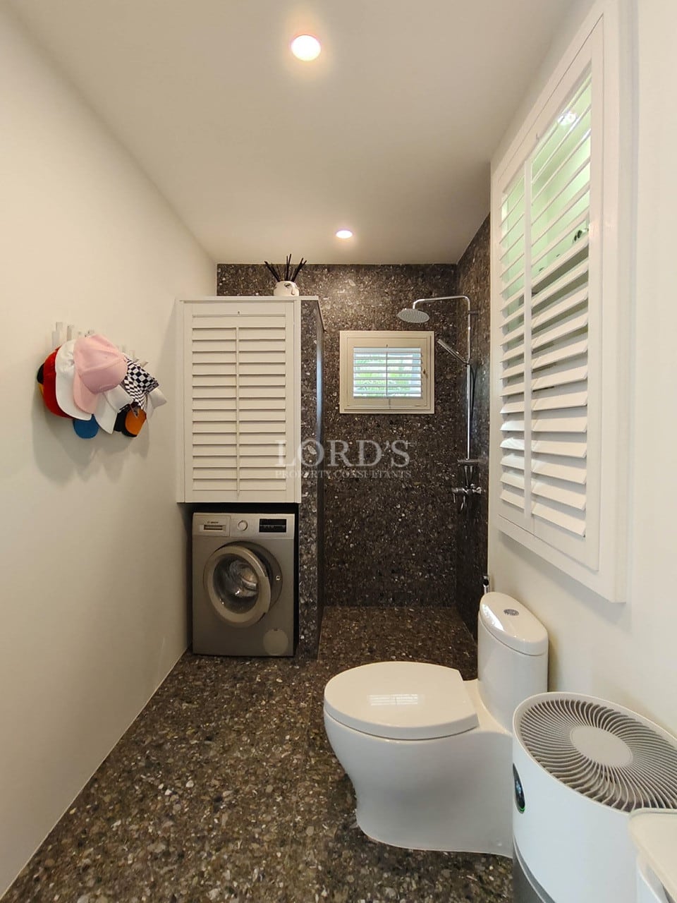 Modern bathroom with walk-in shower, washing machine, stone finishes, and compact layout.
