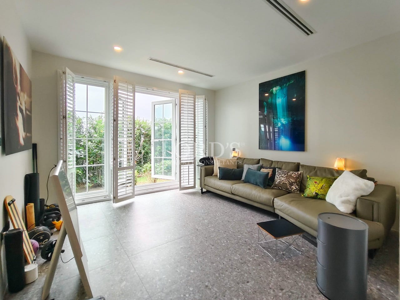 Bright lounge room with sectional sofa, contemporary artwork, and French doors opening to a private garden.
