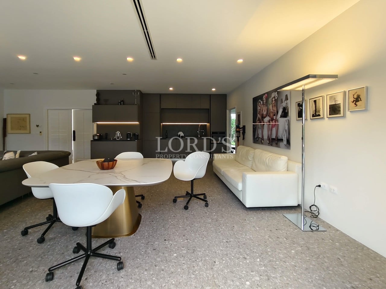 Open-plan dining and living area with modern furniture, designer lighting, and contemporary kitchen.