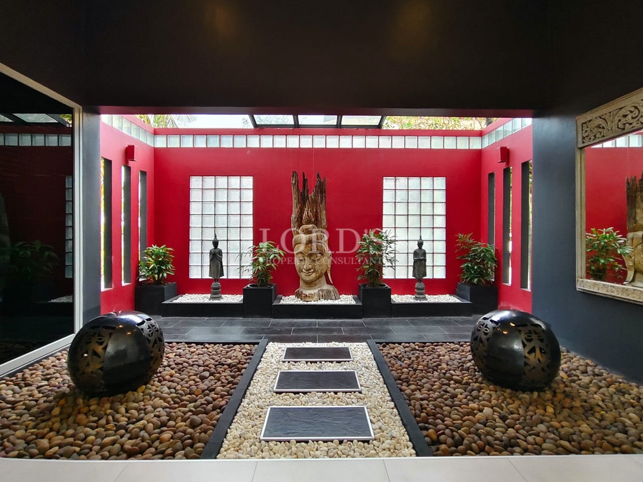 Zen courtyard with Buddha sculpture, pebble garden, and red accent walls.