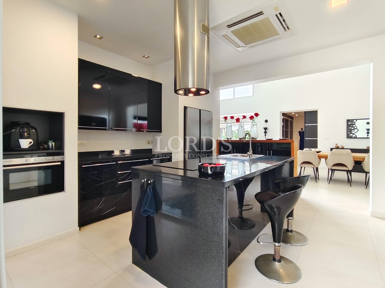 Modern luxury kitchen with black cabinets, island counter, and bar stools.