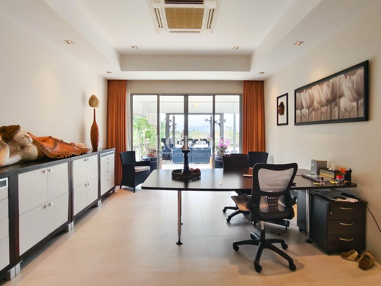 Modern villa home office with large desk, seating area, and garden-facing glass doors.