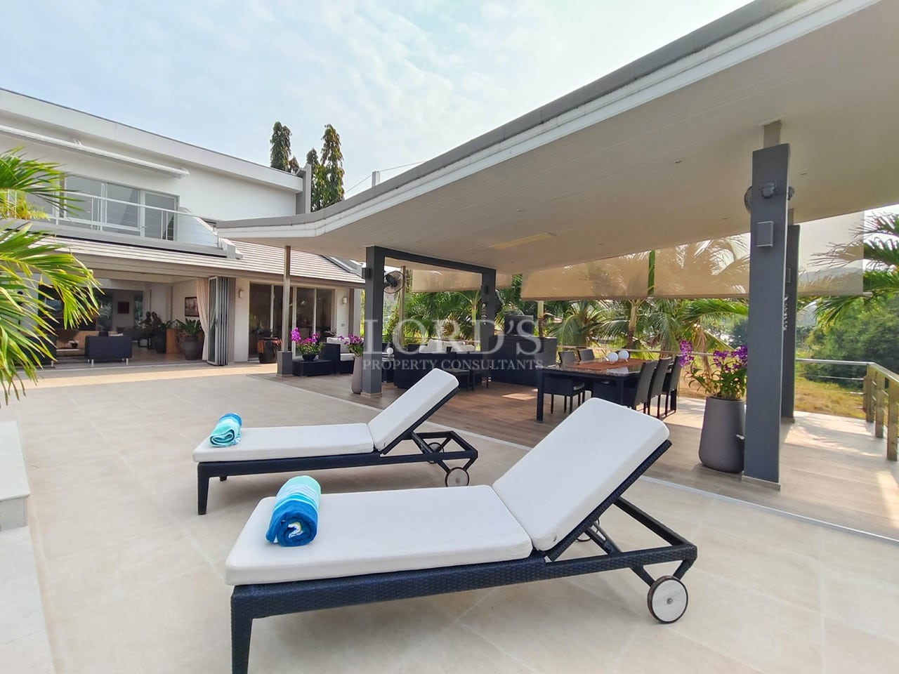 Luxury villa sun loungers on a spacious outdoor terrace with covered dining area.