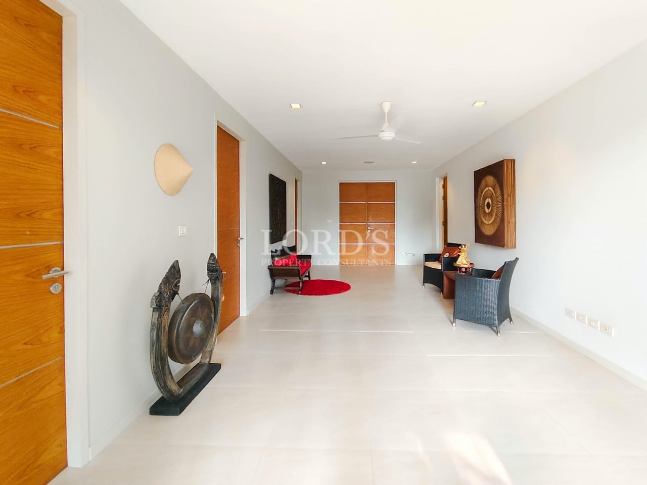 Modern villa hallway with wooden doors, decorative art, and seating area.