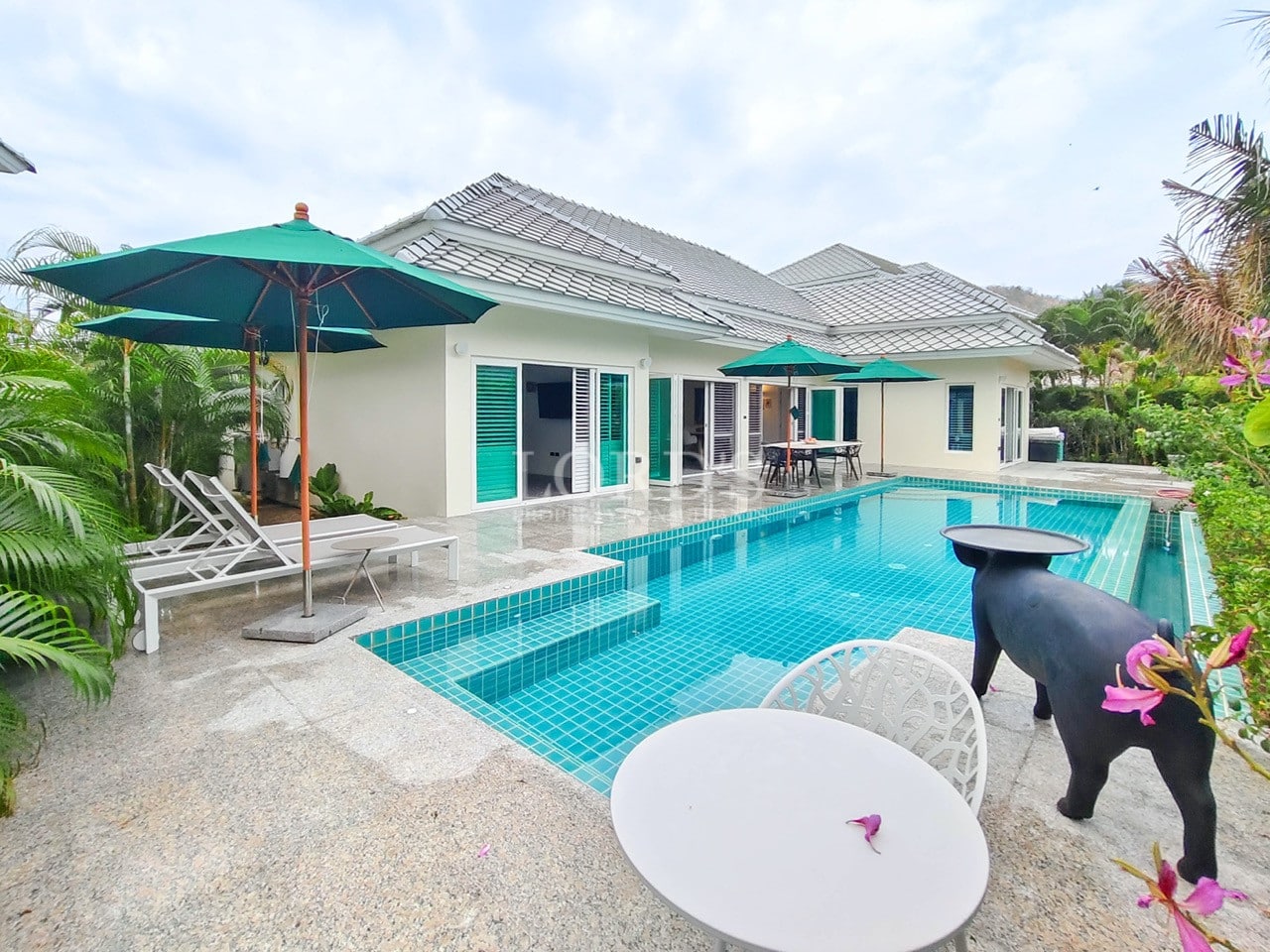Luxury private pool villa with sun loungers, outdoor seating, and tropical landscaping.