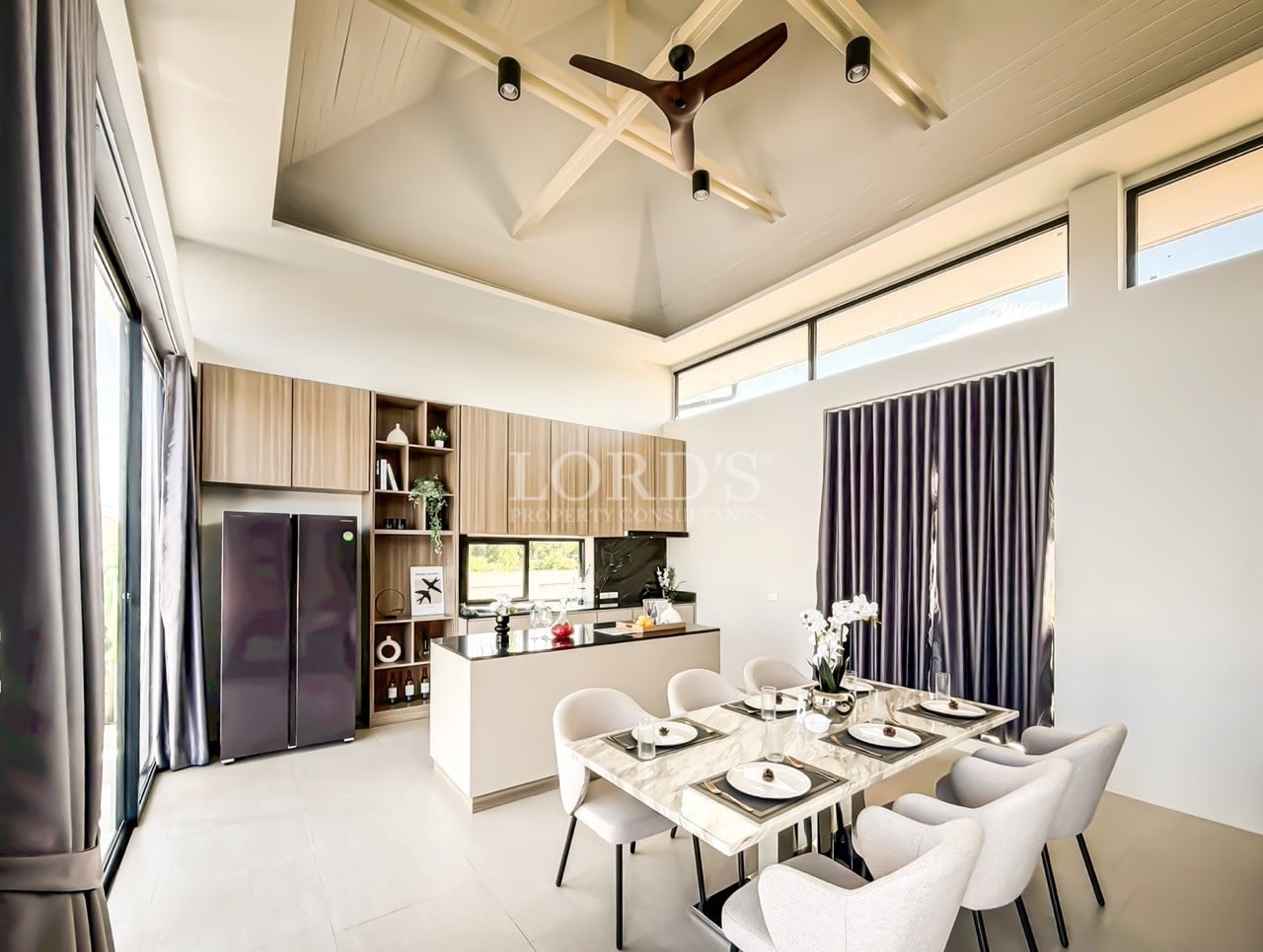 Modern dining area with marble table, open kitchen, high ceiling, and ceiling fan
