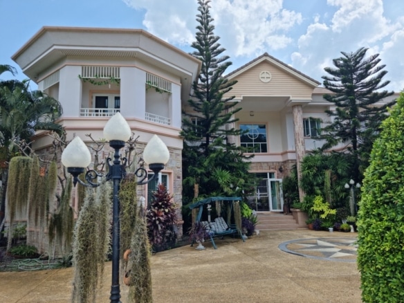 Luxury two-story villa exterior with landscaped garden, driveway, and classic architectural design.