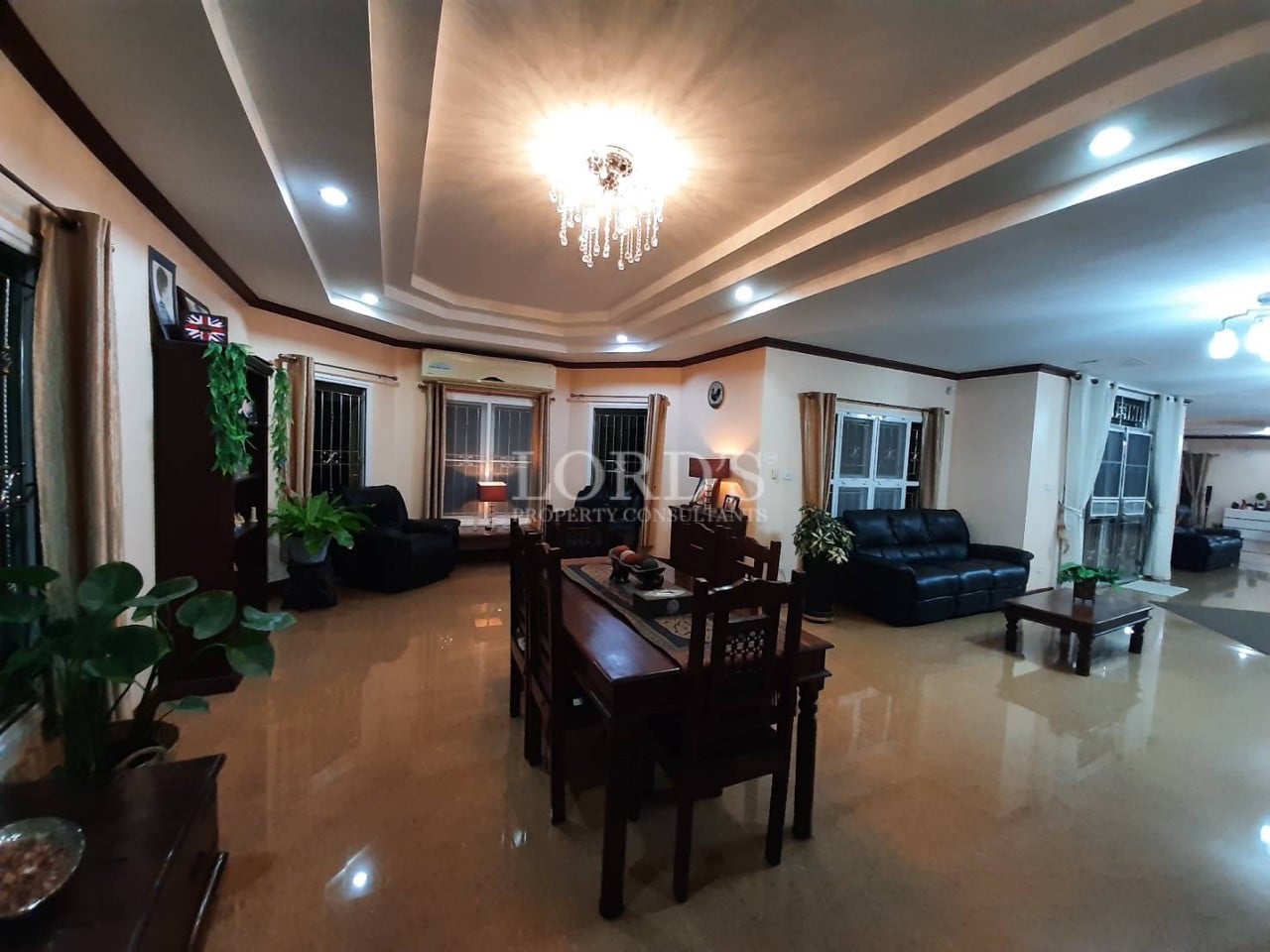 Luxury open-plan living and dining room with crystal chandelier, recessed ceiling, and modern furniture.
