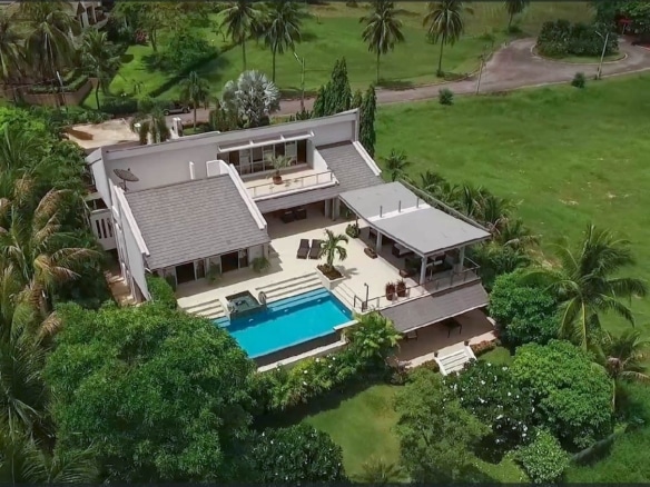 Aerial view of a modern luxury villa with a private swimming pool surrounded by lush tropical greenery.