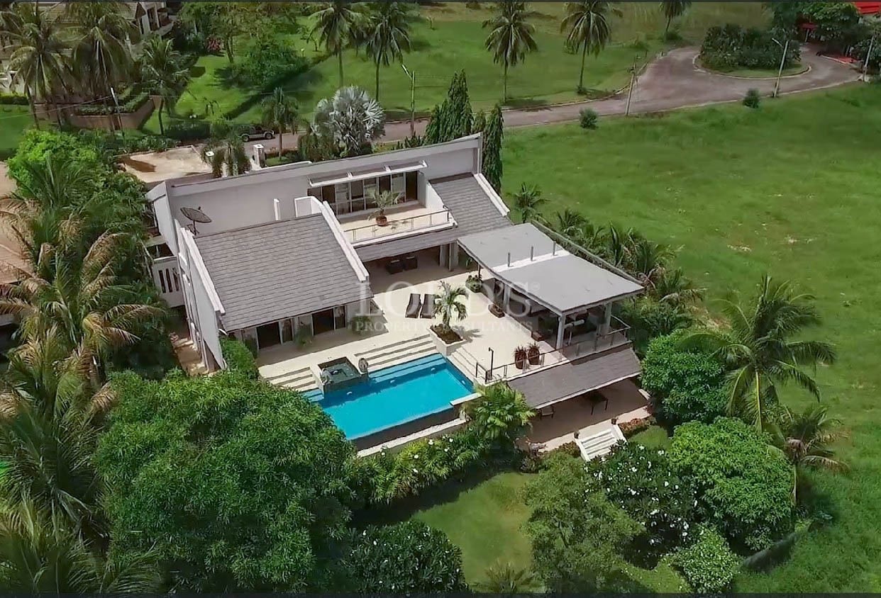 Aerial view of a modern luxury villa with a private swimming pool surrounded by lush tropical greenery.